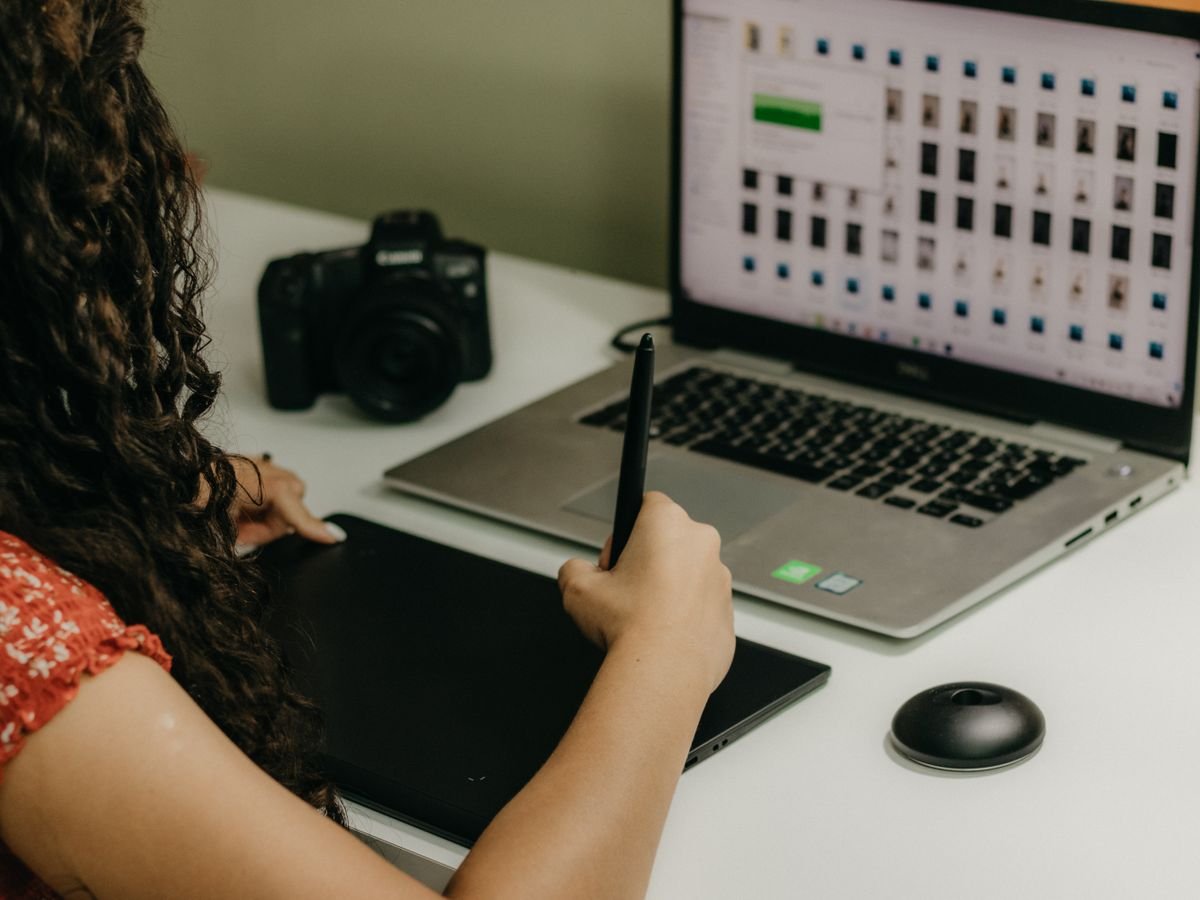 An Artivo designer working at a desk with a drawing tablet, laptop, and camera