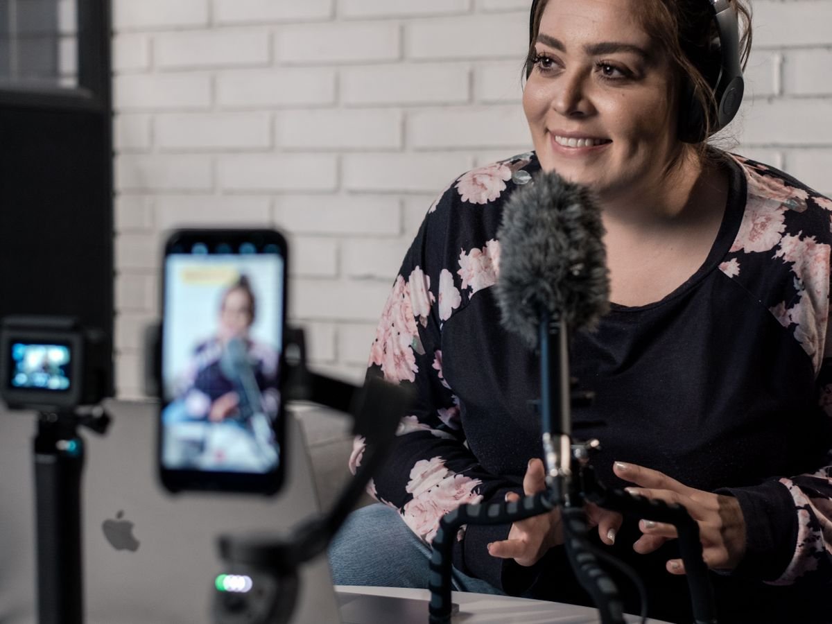 A creator recording a podcast episode with a studio microphone and camera