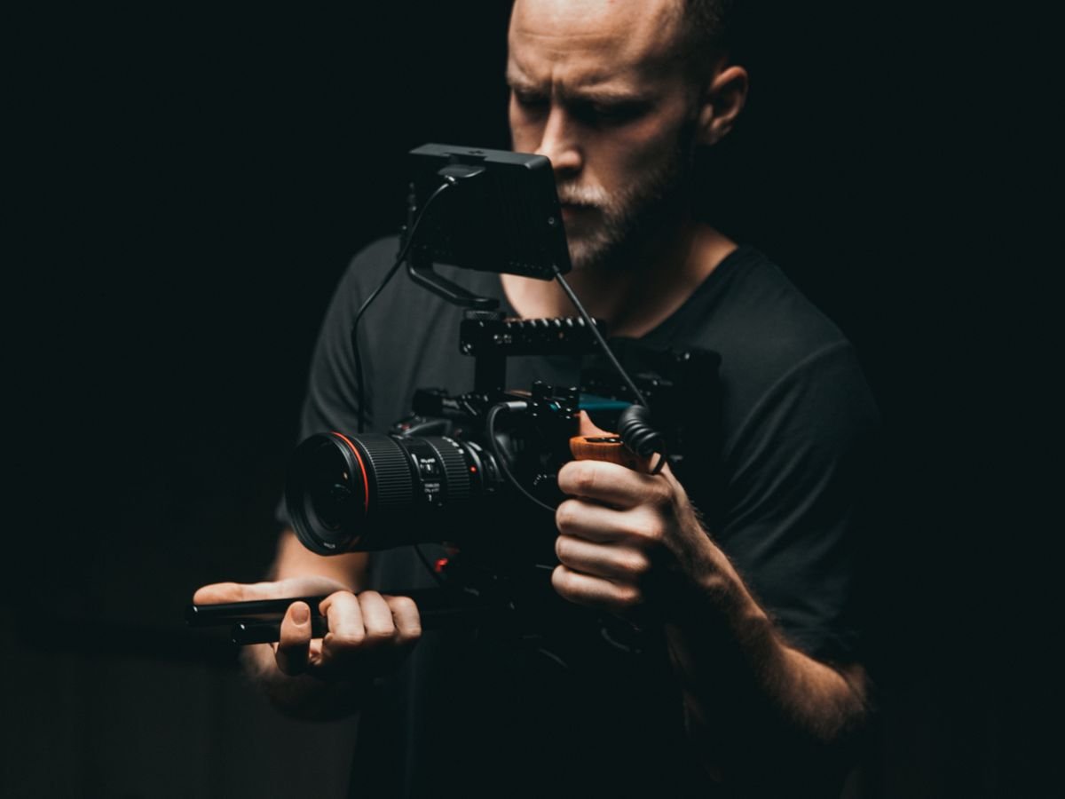 A cinematographer operating a gimbal-mounted camera on a dimly lit set